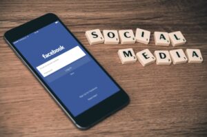 Smartphone with Facebook login screen and scrabble letters "SOCIAL MEDIA".