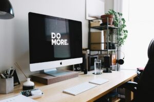 Modern office desk with iMac displaying "Do More.