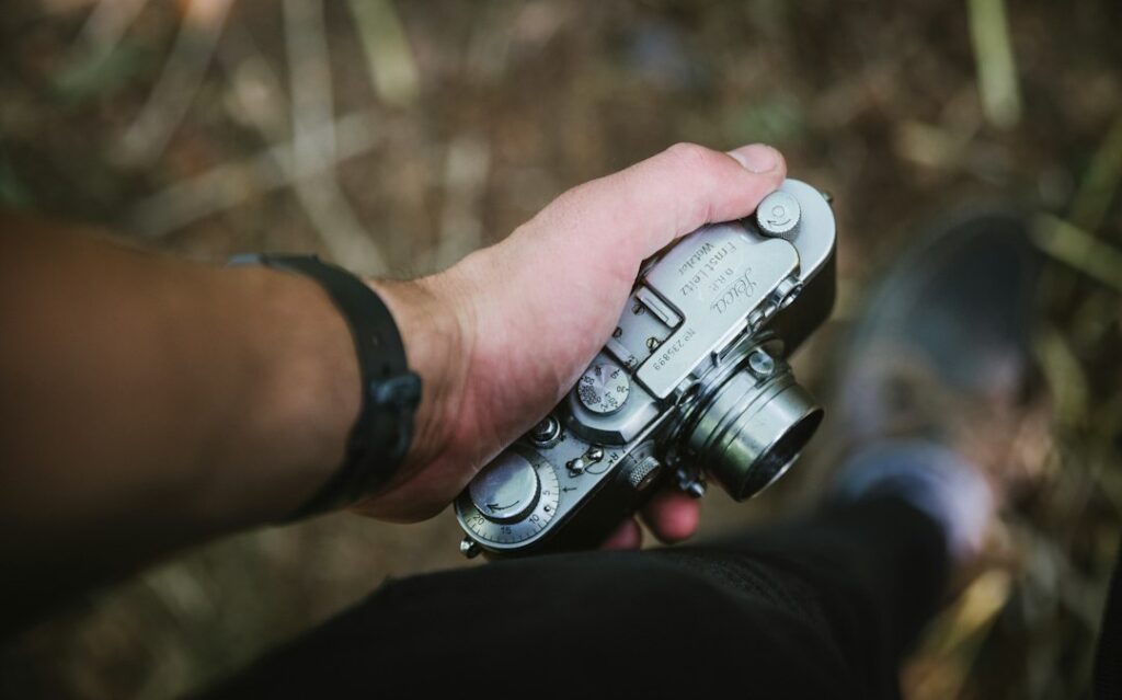 Hand holding vintage camera in nature.