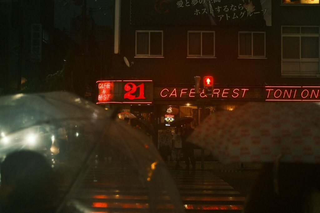 Rainy city street with neon cafe signs at night.