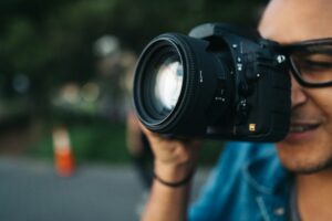 Person holding a camera lens facing forward.
