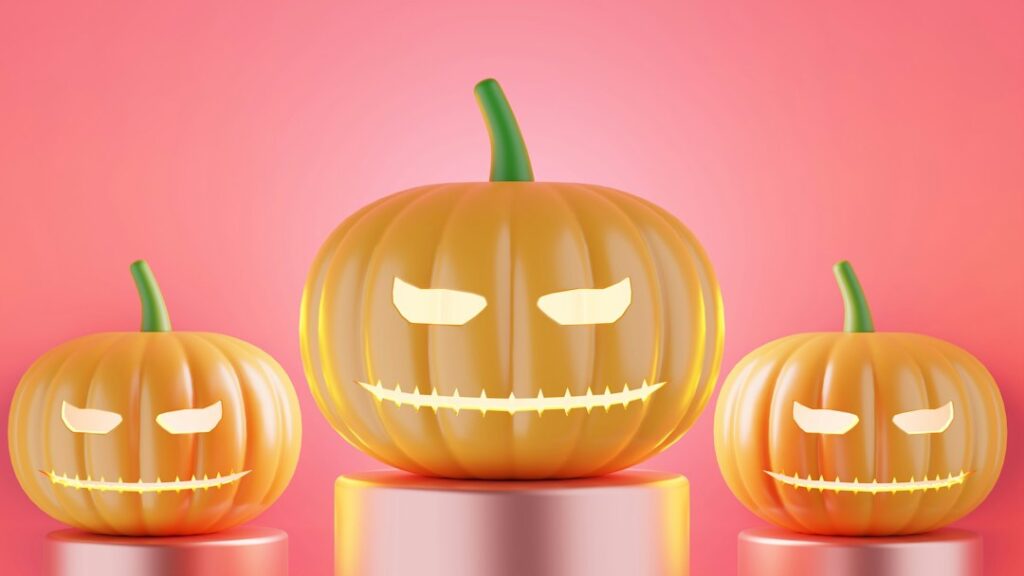 Three carved pumpkins on pink background.