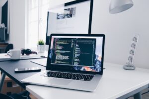 Laptop with code on screen in modern workspace.