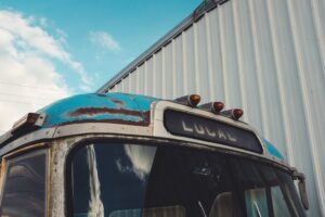 Vintage bus with "LOCAL" sign and rusty roof.