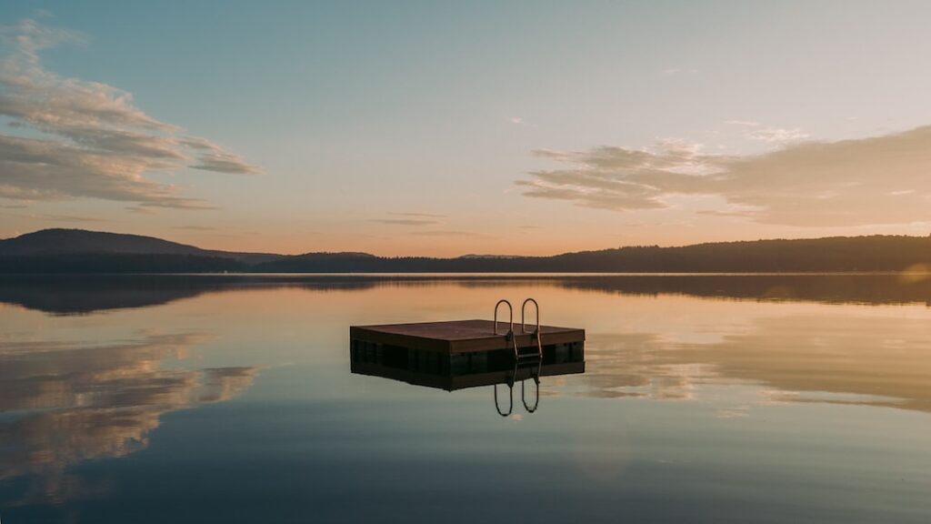 Calm lake with floating dock at sunrise.