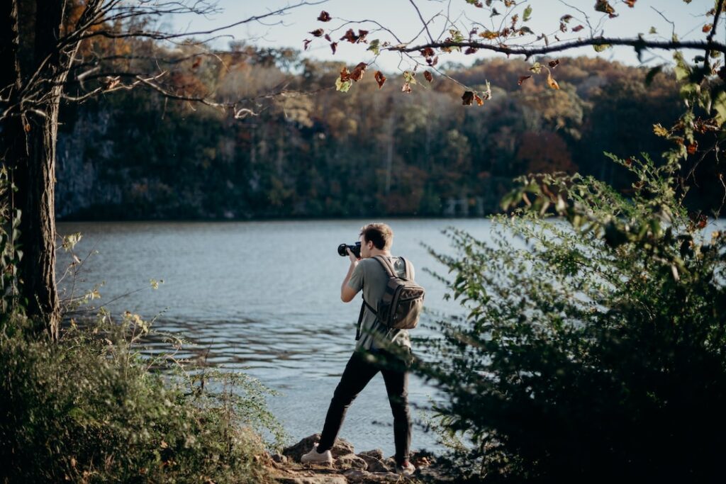 Photographer capturing scenic lake in autumn.