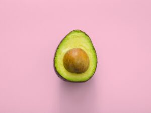 Halved avocado on pink background.