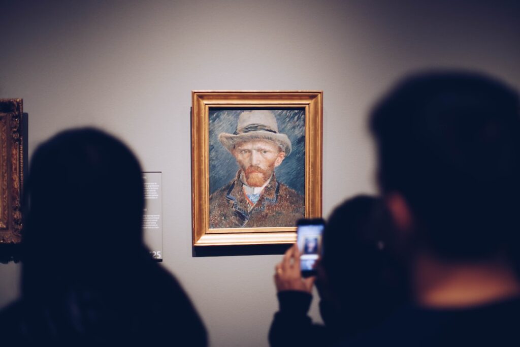 Visitor photographing Van Gogh painting in gallery.