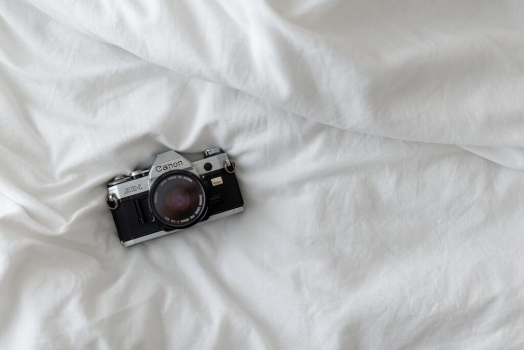 Vintage Canon AE-1 camera on white bedsheet.
