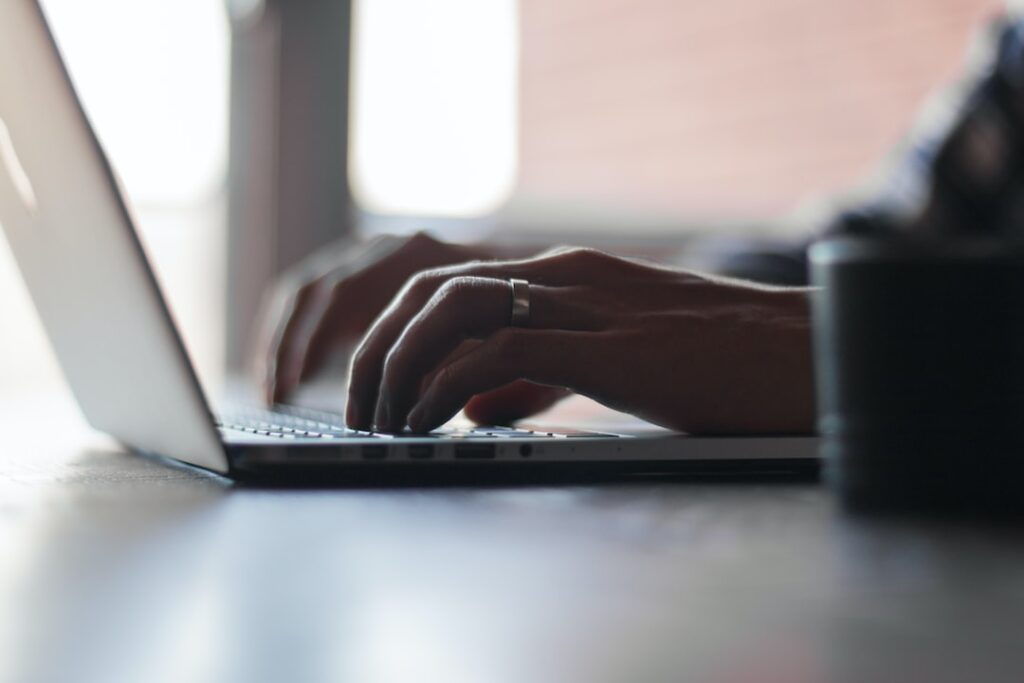 Close-up of hands typing on laptop keyboard.
