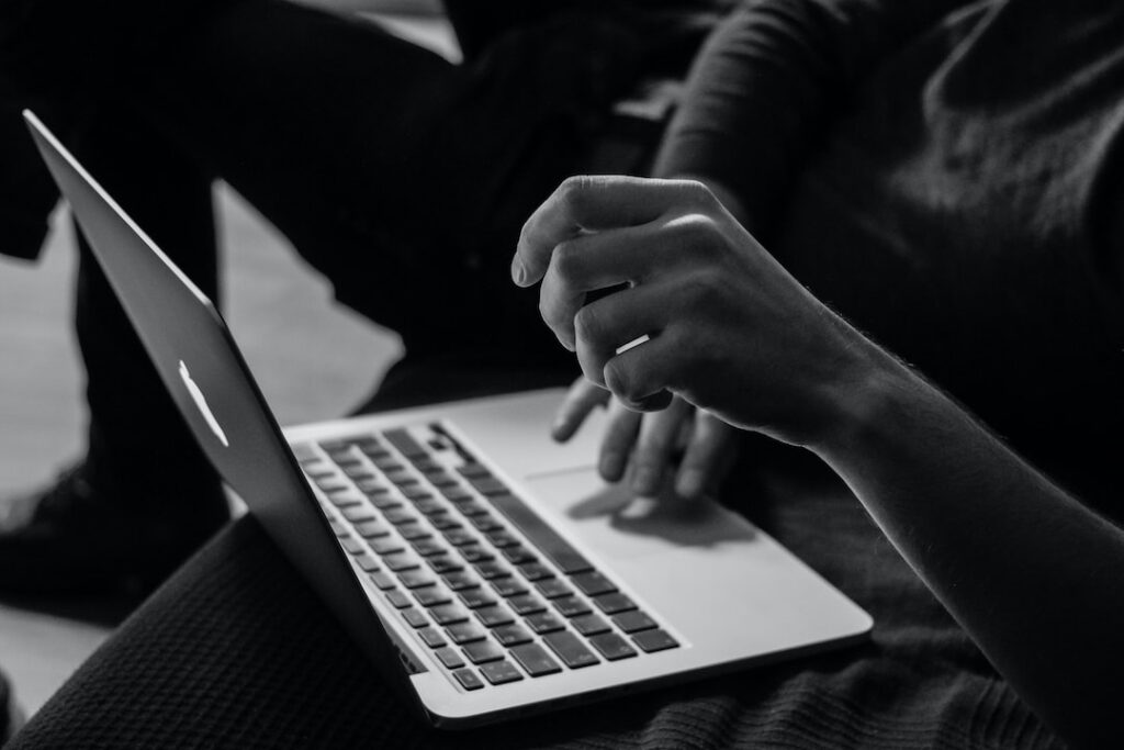 Person typing on laptop, black and white photo.
