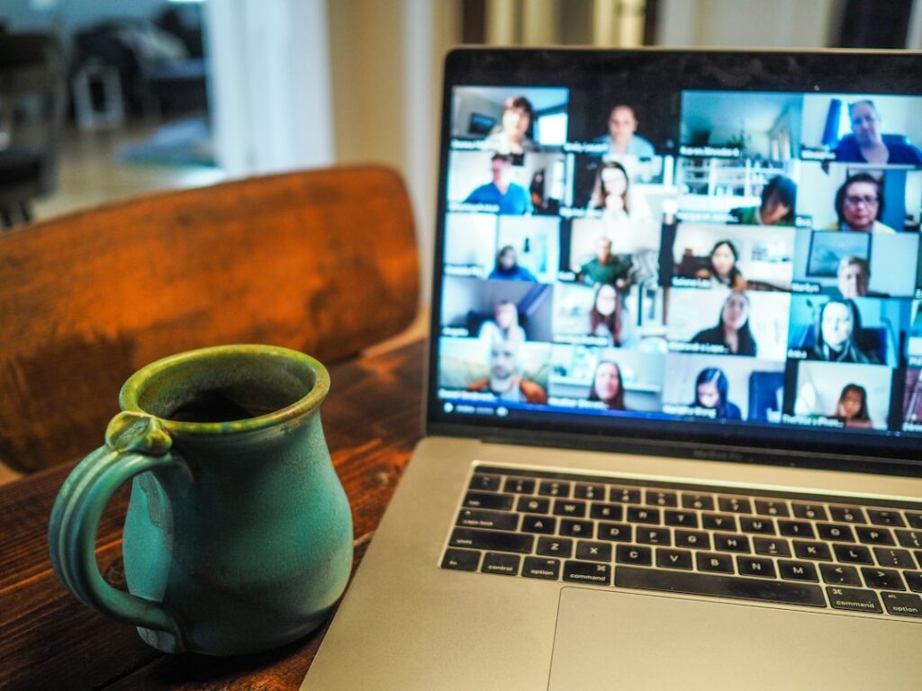 Laptop showing virtual group meeting beside a coffee mug.