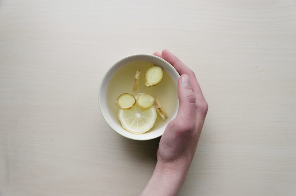 Hand holding lemon ginger tea in bowl.