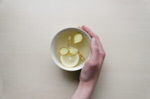 Hand holding lemon ginger tea in bowl.