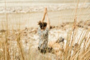 Person relaxing behind beach grass dunes.