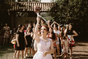 Bride tossing bouquet to guests at outdoor wedding.