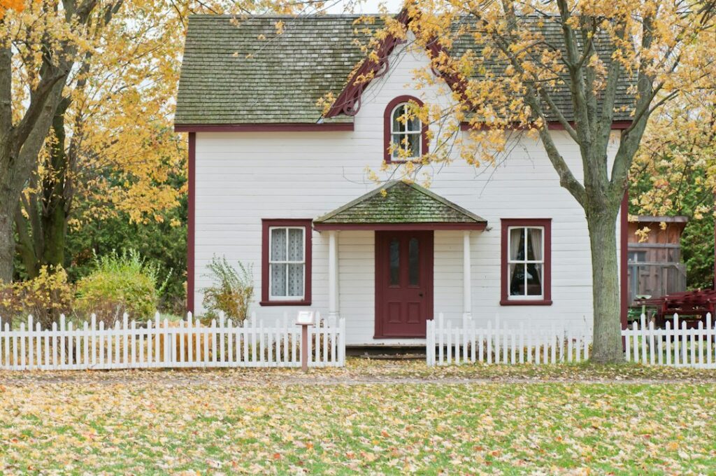 Traditional white house with picket fence in autumn.