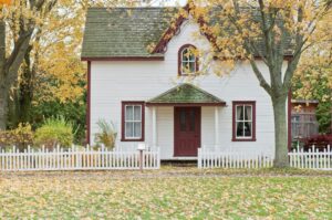 Traditional white house with picket fence in autumn.