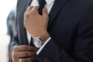 Man adjusting tie wearing elegant watch.