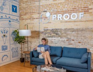 Man reading on couch in modern office with mural.