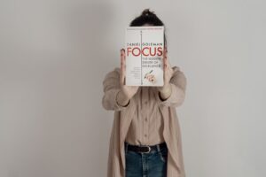 Person holding "Focus" book covering face.
