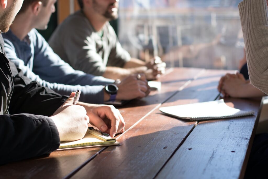 Group meeting with notepads on wooden table.