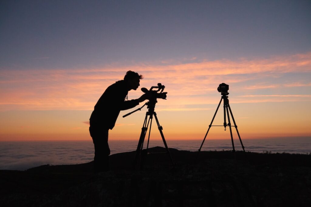 Silhouette of photographer with tripods at sunset.