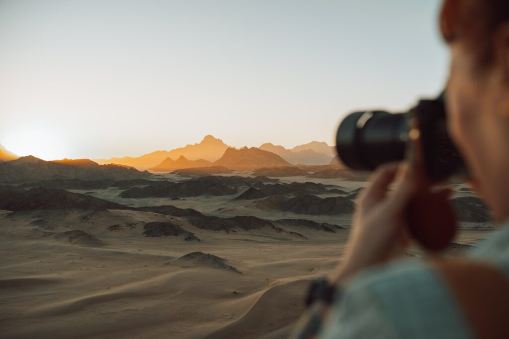Photographer capturing sunset over desert landscape