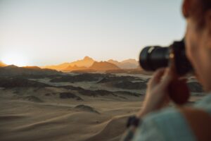 Photographer capturing sunset over desert landscape