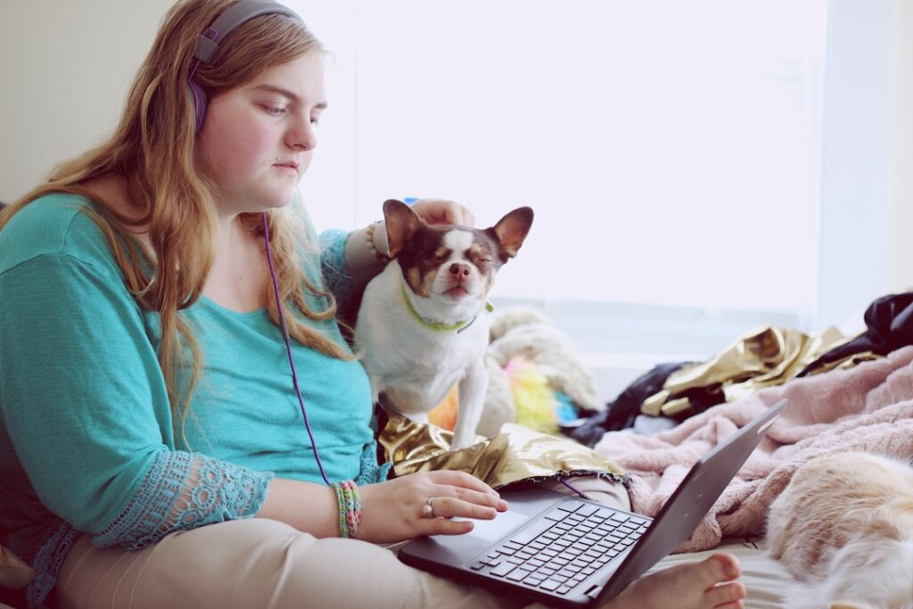 Woman with dog using laptop at home.