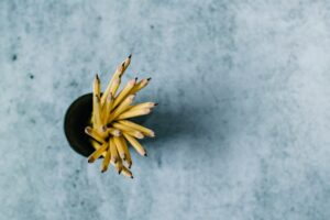 Pencils in cup overhead view on textured background.