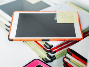 Tablet with orange case among stationary items.