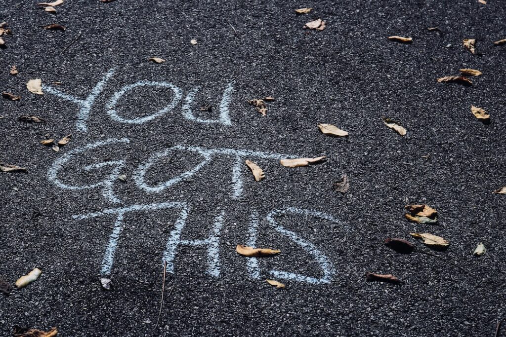 Inspirational "You Got This" written on pavement with leaves.