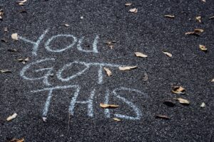 Inspirational "You Got This" written on pavement with leaves.
