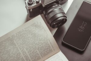 Vintage camera, open book, and smartphone on table.