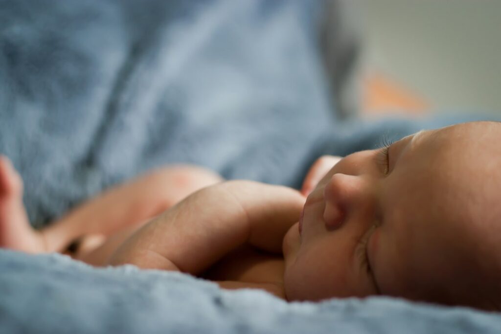 Newborn sleeping peacefully on blue blanket.