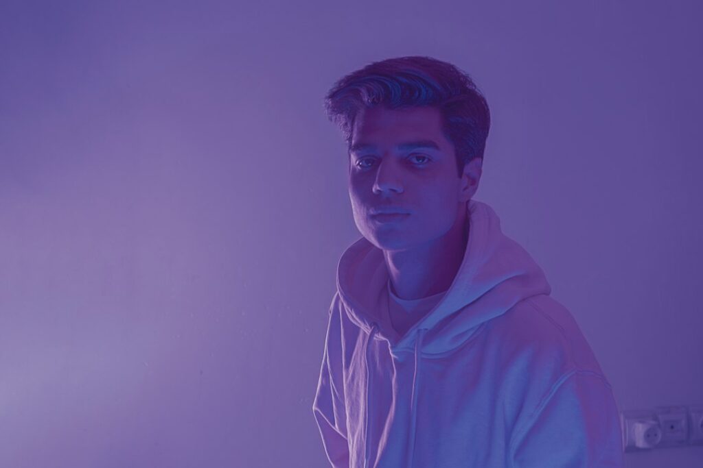 Young man in hoodie with purple lighting