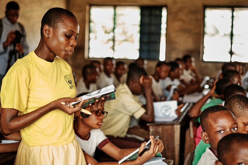 Student reading book in crowded classroom.