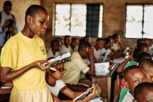 Student reading book in crowded classroom.